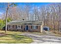 View of the brick home with a driveway leading to a detached garage in a wooded setting at 2913 Archdale Dr, Charlotte, NC 28210