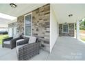 Relaxing covered porch featuring stone accents, two comfortable chairs, and ample space at 50 Sherwood Nw Ct # Sw50, Concord, NC 28027