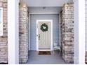 Close-up of the front door showcasing stone columns, stylish wreath, and a welcome mat, creating a charming entrance at 527 Morrows Turnout Way, Pineville, NC 28134