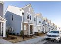 Street view showcasing a row of modern townhomes with light blue siding and stone accents, with sidewalks and landscaping at 527 Morrows Turnout Way, Pineville, NC 28134