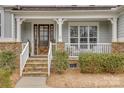 Inviting covered front porch with stone stairs, white railing and a decorative wood and glass front door at 5431 Meadowcroft Way, Fort Mill, SC 29708