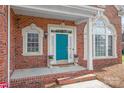 Close-up of brick house with blue door, portico entrance, and manicured landscaping at 7925 Tottenham Dr, Harrisburg, NC 28075