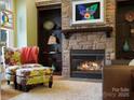 Cozy living room with a stone fireplace, built-in bookshelves, and a comfortable chair with colorful floral pattern at 8416 Highgrove St, Charlotte, NC 28277
