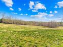 Vast grassy field with a small road, surrounded by trees and a clear blue sky with fluffy clouds at 164 Linderman Lake Ln, Kings Mountain, NC 28086