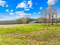 View of outbuilding on a grassy field with a road, trees and a clear blue sky with fluffy clouds at 164 Linderman Lake Ln, Kings Mountain, NC 28086