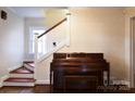 Inviting entryway features a wooden staircase, piano, and a friendly feline companion at 215 Biscoe Rd, Troy, NC 27371