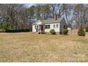 Quaint single-story home showcasing a chimney, surrounded by a green lawn and trees at 27 Liske Nw Ave, Concord, NC 28027