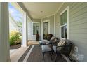 Inviting covered front porch featuring seating, a stylish rug, and views of the landscaped yard at 4922 Looking Glass Trl, Denver, NC 28037