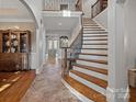 Grand foyer showcasing an elegant staircase with iron railings and tiled floor, setting a tone of sophistication at 8724 Highgrove St, Charlotte, NC 28277