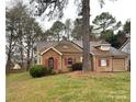 Single-story home featuring brick and tan siding, red shutters, and mature trees at 2517 Bushy Pine Ct, Charlotte, NC 28273