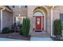Close up of a red front door with arched window, surrounded by brick and manicured bushes at 3815 10Th Ne St, Hickory, NC 28601