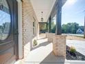 Inviting front porch featuring brick columns and contemporary lighting, ideal for relaxation and enjoying the outdoors at 588 Washington Ln, Albemarle, NC 28001