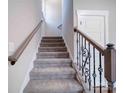 Carpeted staircase with decorative iron railings and wooden accents, offering a stylish transition between floors at 588 Washington Ln, Albemarle, NC 28001