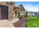 Beautiful home featuring a stone facade, a covered porch, and landscaped garden at 7127 Hanging Rock Ct, Denver, NC 28037