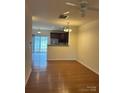 Open-concept living room with hardwood floors, a ceiling fan, and abundant natural light at 7141 Adare Mews Rd, Charlotte, NC 28217