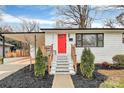 Close-up of a white brick home featuring a vibrant red front door and striped steps with wood railings at 914 Crestmere St, Charlotte, NC 28208