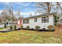 Angle view of a well-maintained single-story home with white brick, tidy landscaping, and a red front door at 914 Crestmere St, Charlotte, NC 28208