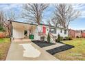 View of a white brick home with a carport, showcasing updated landscaping and a bright red front door at 914 Crestmere St, Charlotte, NC 28208