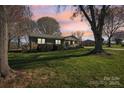 Brick home surrounded by mature trees and lush lawn at dusk provides tranquility at 108 Colonial Dr, Kings Mountain, NC 28086