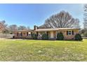 Charming brick home with manicured lawn, mature trees, and updated black shutters and trim at 1356 Ford Dr, Lowell, NC 28098