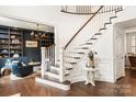 Elegant foyer with hardwood floors, curved staircase, and view into a study with built in bookcases at 2007 Fernhurst Ter, Matthews, NC 28104