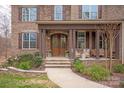 Inviting front porch showcasing a stone entryway, wooden pillars, and cozy seating area at 2007 Fernhurst Ter, Matthews, NC 28104