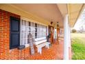 Inviting front porch showcases a cozy seating area with bench and columns, complemented by red brick and patterned tiles at 30 Hillsboro Rd, Taylorsville, NC 28681