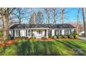 Charming single-story home boasts meticulously landscaped front yard and cozy rocking chairs on the porch at 3830 Lovett Cir, Charlotte, NC 28210