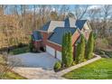 Aerial view of a brick home with a spacious driveway, landscaping, and a three-car garage at 653 Buckleigh Nw Ct, Concord, NC 28027