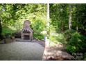 Beautiful stone patio with an outdoor fireplace and landscaped surroundings perfect for entertaining at 653 Buckleigh Nw Ct, Concord, NC 28027