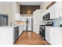 Bright kitchen featuring stainless steel appliances, white cabinets, light backsplash, and wood flooring at 7047 Whittingham Dr, Indian Land, SC 29707