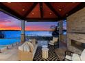 Cozy outdoor lounge with a fireplace, wicker furniture, and stunning lake views at sunset at 18601 Bluff Point Rd, Cornelius, NC 28031