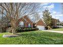 Inviting brick home with a two-car garage, manicured lawn, and mature trees surrounding the property at 2713 Firethorn Ct # 48, Gastonia, NC 28056