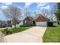Well-maintained brick home featuring a lush green lawn, long driveway, and mature trees at 2713 Firethorn Ct # 48, Gastonia, NC 28056