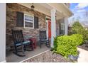 Inviting front porch with stone accents, rocking chairs, and a vibrant red door adding a pop of color at 4035 W Sandy Trl, Fort Mill, SC 29707