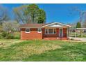Quaint brick home with a covered front porch and a well-maintained lawn at 602 Dallas Spencer Mountain Rd, Dallas, NC 28034