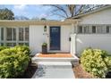 Close-up of a blue front door with brick steps, lush landscaping, and a welcoming entrance at 6136 Montpelier Rd, Charlotte, NC 28210