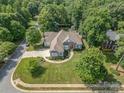 Stunning aerial view of a landscaped property with a circular driveway, mature trees, and lush green lawns at 7913 Buena Vista Dr, Denver, NC 28037