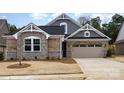 Charming home exterior showcasing a stone and gray facade, well-manicured lawn, and a spacious driveway at 9534 Liberty Hill Dr # 196, Mint Hill, NC 28227