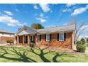 Classic brick home with black shutters, complemented by a lush green lawn and mature landscaping for enhanced curb appeal at 1558 Pine Creek Rd, Gastonia, NC 28056