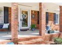 Inviting front porch with brick columns, featuring a decorative wreath on the glass door and charming outdoor decor at 1558 Pine Creek Rd, Gastonia, NC 28056