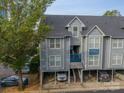 View of the exterior of the condo showing parking, siding, stairs, and a mature tree at 513 N Graham St # 3H, Charlotte, NC 28202