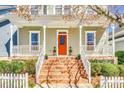 A detailed close up of a home's welcoming front porch with an orange door and lush landscaping at 122 Blandina Ct, Fort Mill, SC 29708