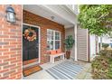 Cozy front porch featuring a brick facade, decorative wreath, and a striped rug over the concrete at 130 Clydesdale Ct, Matthews, NC 28104