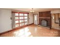 Bright living room featuring a brick fireplace, hardwood floors, and a large window at 142 Wilson Ne St, Concord, NC 28025