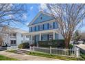 Attractive two-story home showcasing a covered front porch, blue siding, complemented by lush greenery and a white picket fence at 3208 Fifth Baxter Xing, Fort Mill, SC 29708