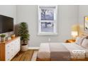 Cozy bedroom with hardwood floors, a comfortable bed, a dresser, and a large window at 325 Oregon St, Charlotte, NC 28208