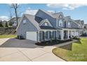 View of home showcasing three-car garage and neatly landscaped yard with a sidewalk at 8638 Raven Top Dr, Mint Hill, NC 28227