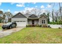 Charming home featuring stone accents, covered porch, two-car garage and nicely maintained lawn at 125 Jefferson Dr, Locust, NC 28097