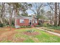 Charming red brick home with walkway and a beautifully landscaped yard featuring a white bench and blooming flowers at 1817 Jameston Dr, Charlotte, NC 28209